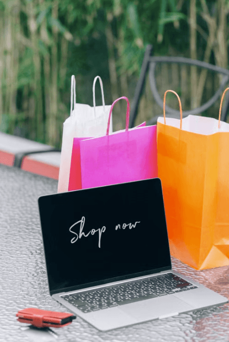 Shopping bags beside a laptop showing Shop now